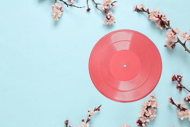 Disco de vinilo retro con hermosas ramas de flores blancas sobre fondo azul pastel Concepto de música mínima de primavera Vista superior plana Espacio de copia