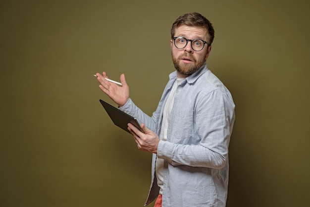 Discusión de la idea Hombre barbudo serio con gafas con una tableta en una mano y un lápiz en la otra