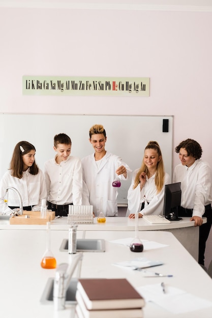 Discusión con un maestro en una lección de química en un laboratorio Grupo de compañeros de clase están discutiendo experimentos de química y tareas en la escuela Concepto de educación