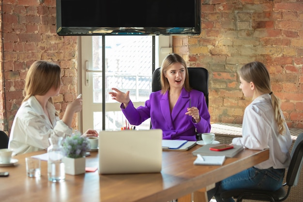 Discusión. Mujer de negocios caucásica joven en la oficina moderna con el equipo. Reunión, entrega de tareas. Mujeres en el trabajo de recepción. Concepto de finanzas, negocios, poder femenino, inclusión, diversidad, feminismo.