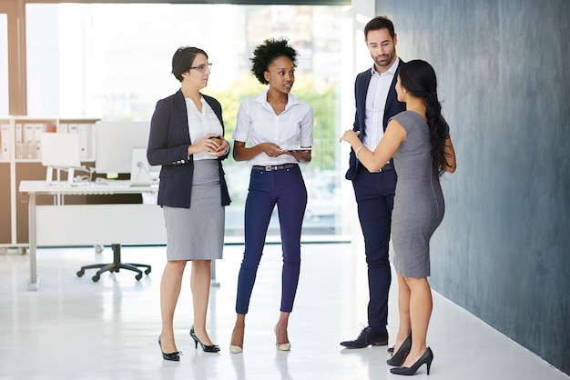 Discusiones en el lugar de trabajo Toma completa de un grupo de empresarios hablando en la oficina