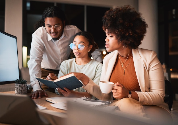 Foto discussão de cadernos e empresários no escritório à noite para projeto criativo de trabalho em equipe conversa de leitura e designers profissionais trabalhando horas extras em colaboração para pesquisa no local de trabalho