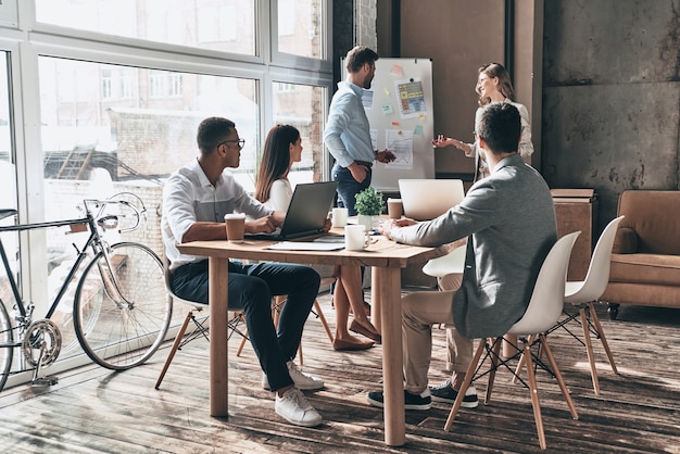 Discutindo ideias arriscadas. Dois jovens colegas conduzindo uma apresentação de negócios usando flipchart