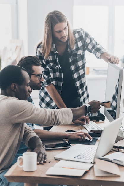 Discutindo novas abordagens. Grupo de jovens empresários trabalhando e se comunicando enquanto usam tecnologias modernas