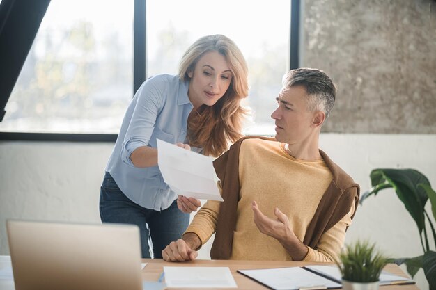 Foto discutindo o projeto um homem e uma mulher no escritório conversando e discutindo um projeto