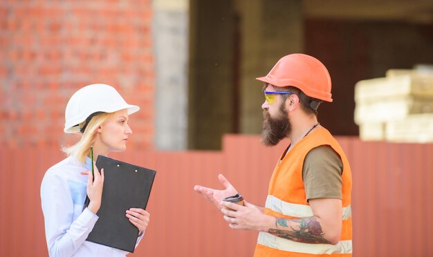 Foto discutir o plano de progresso mulher engenheira e construtor brutal barbudo discutem o progresso da construção conceito da indústria da construção relacionamentos cliente de construção e indústria de construção participante