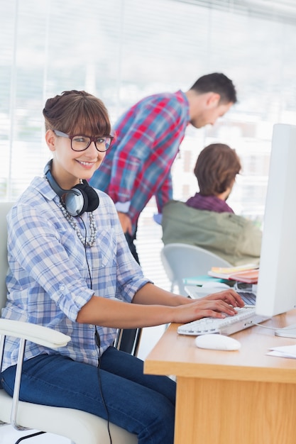 Diseñador bonito con auriculares trabajando en la computadora