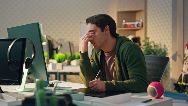 Foto diseñador cansado frotándose los ojos en el lugar de trabajo de la computadora creador con exceso de trabajo trabajando