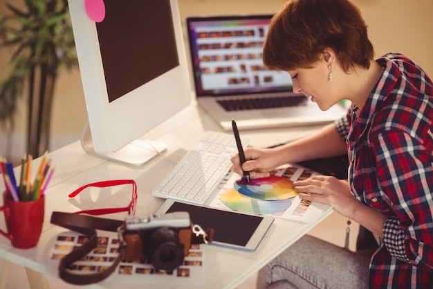 Diseñador casual femenina que trabaja con digitalizador y carta de colores