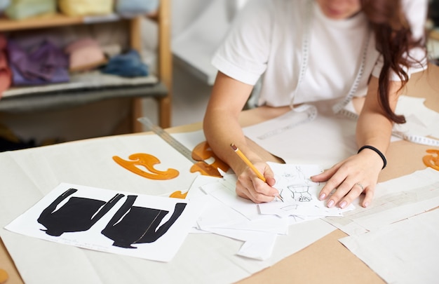 Foto diseñador femenino dibujo bocetos a lápiz de ropa