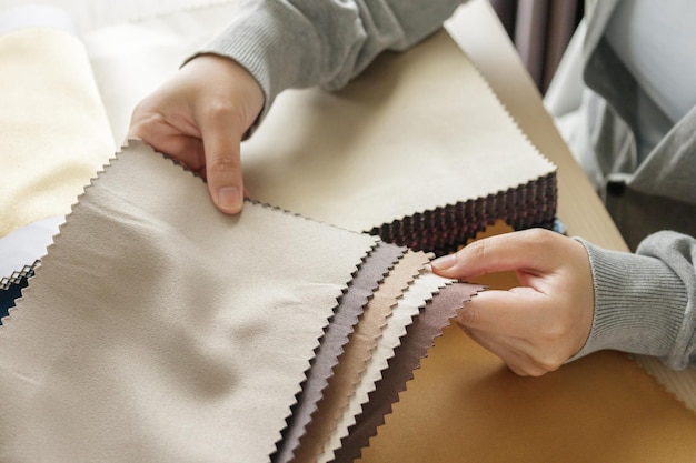 Diseñador femenino con muestras de color de tela eligiendo textiles para cortinas