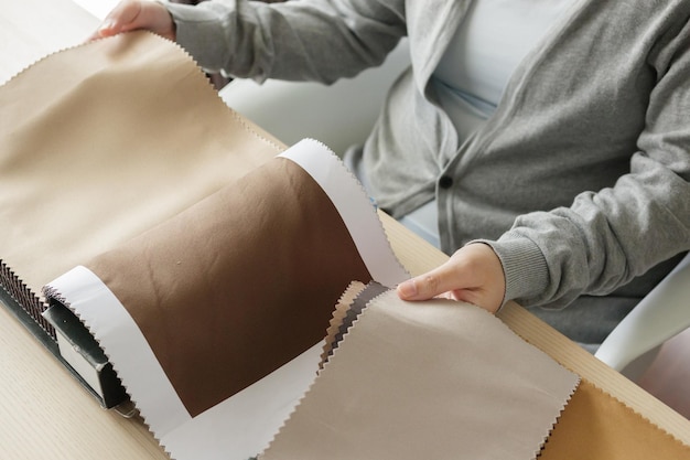 Foto diseñador femenino con muestras de color de tela eligiendo textiles para cortinas