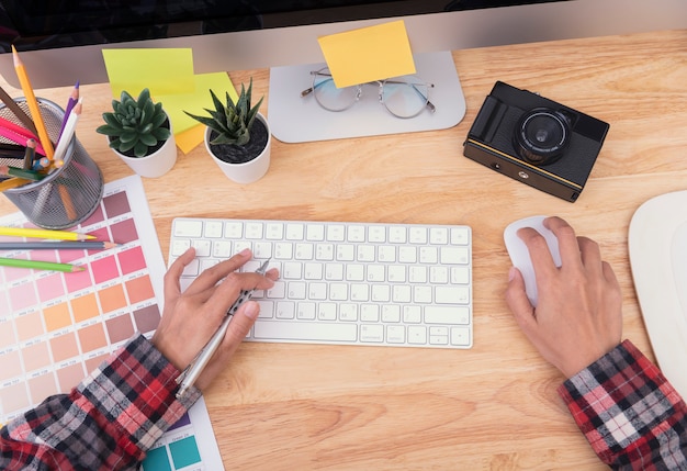 Diseñador gráfico artista manos escribiendo en una computadora de teclado que está sobre un escritorio de madera