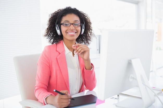 Diseñador gráfico casual trabajando en su escritorio sonriendo a la cámara