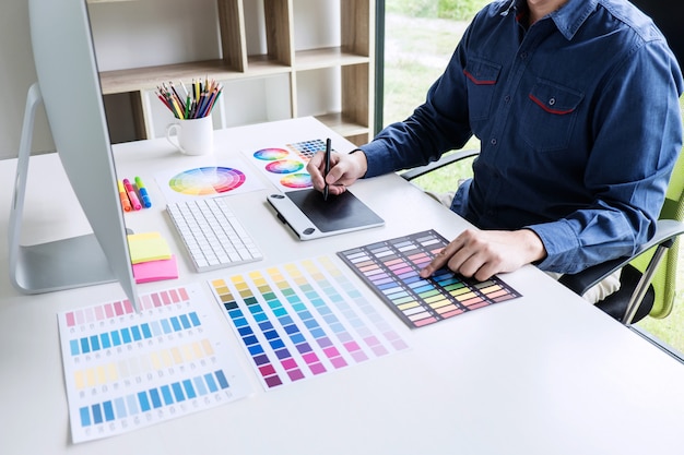Diseñador gráfico creativo que trabaja en la selección de color y dibujo en tableta gráfica en el lugar de trabajo