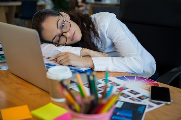 Foto diseñador gráfico femenino cansado que duerme en el escritorio