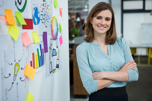 Diseñador gráfico femenino de pie con las manos cruzadas en la oficina creativa