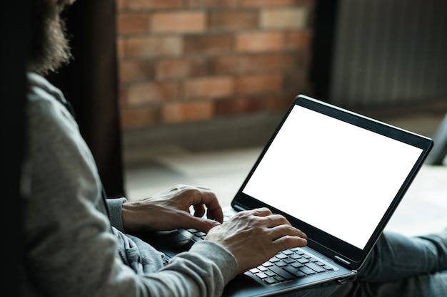 Diseñador gráfico independiente, trabajo remoto, autónomo, hombre que trabaja en una computadora portátil, pantalla blanca en blanco para comercio electrónico