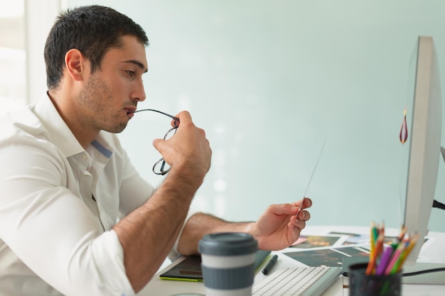 Foto diseñador gráfico masculino mirando fotos en el escritorio de la oficina