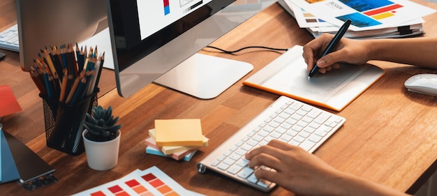 El diseñador gráfico trabaja en una computadora portátil con bolígrafo digital