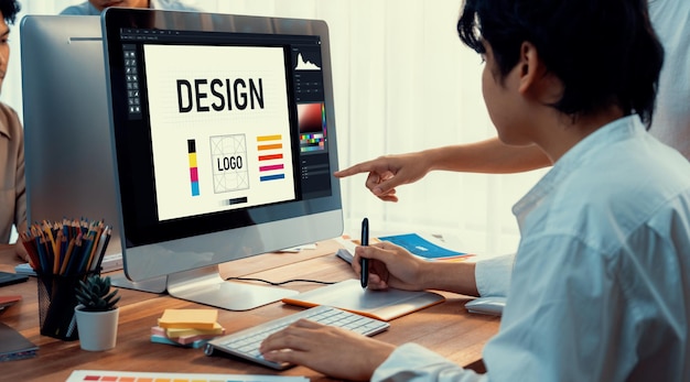 El diseñador gráfico trabaja en una computadora portátil y con un lápiz de dibujo gráfico mientras hace una lluvia de ideas sobre un diseño único con un equipo gráfico profesional en un lugar de trabajo de estudio digital moderno Toma panorámica Escudriñar
