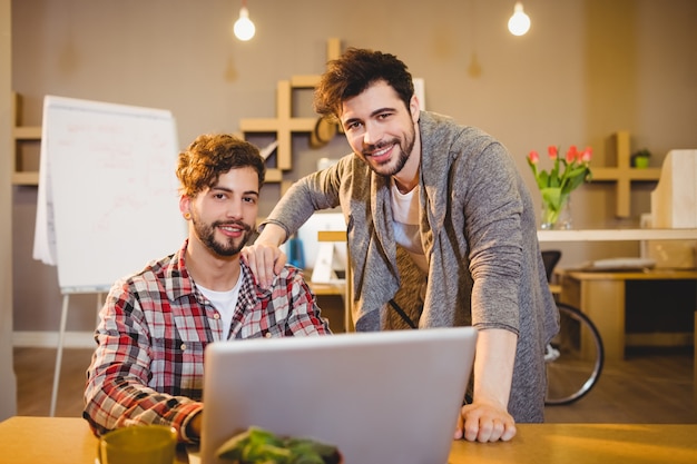 Foto diseñador gráfico usando laptop con su compañero de trabajo