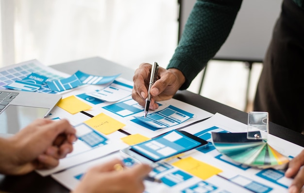 El diseñador de la interfaz de usuario y el diseñador del equipo de desarrolladores de la experiencia de usuario hacen una lluvia de ideas sobre el diseño de estructura alámbrica de la interfaz de la aplicación móvil con el código de color y el resumen del cliente en la oficina modernaxA