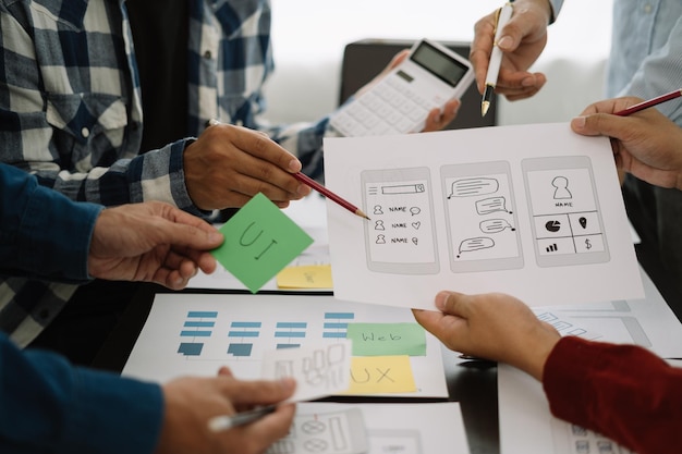 diseñador de interfaz de usuario haciendo una lluvia de ideas sobre el diseño de estructura alámbrica de la interfaz de la aplicación móvil con una breve descripción del cliente y un código de colores en la oficina