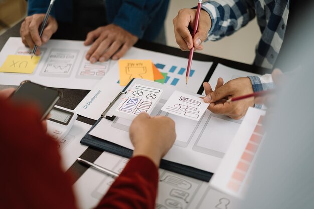 Foto diseñador de interfaz de usuario haciendo una lluvia de ideas sobre el diseño de estructura alámbrica de la interfaz de la aplicación móvil con una breve descripción del cliente y un código de colores en la oficina