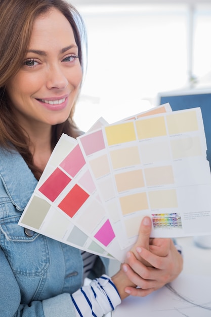 Foto diseñador de interiores alegre sosteniendo muestras de color