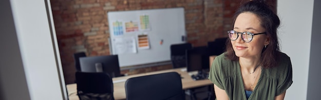 Diseñador de interiores o arquitecto en ropa casual con peinado desordenado sonriendo a un lado mientras trabaja en un