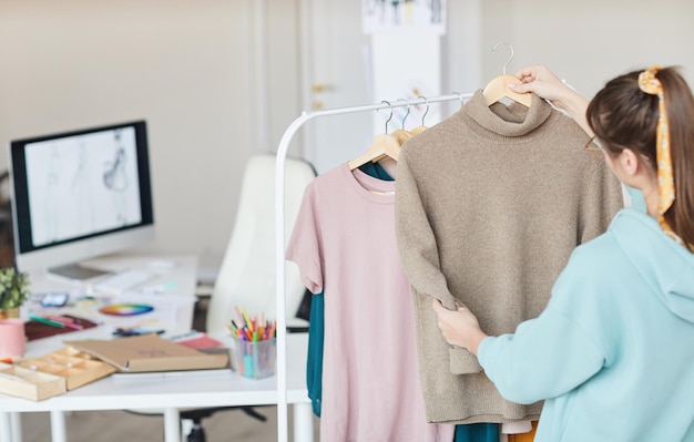 Diseñador de moda eligiendo ropa en taller