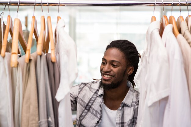 Diseñador de moda masculina que mira el estante de la ropa