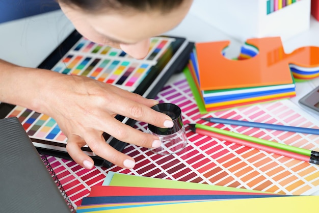 Foto diseñador de niña mirando a través de una lupa en la paleta de colores