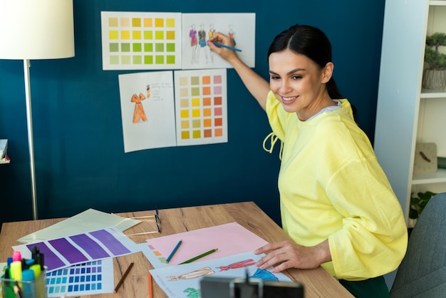 Diseñador profesional concentrado dibujando bocetos de nuevo diseño para ropa elegante mientras está sentado en su propio estudio de taller