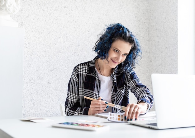 Diseñador que trabaja con paletas de colores y portátil en su estudio de arte