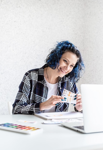 Foto diseñador que trabaja con paletas de colores y portátil en su estudio de arte