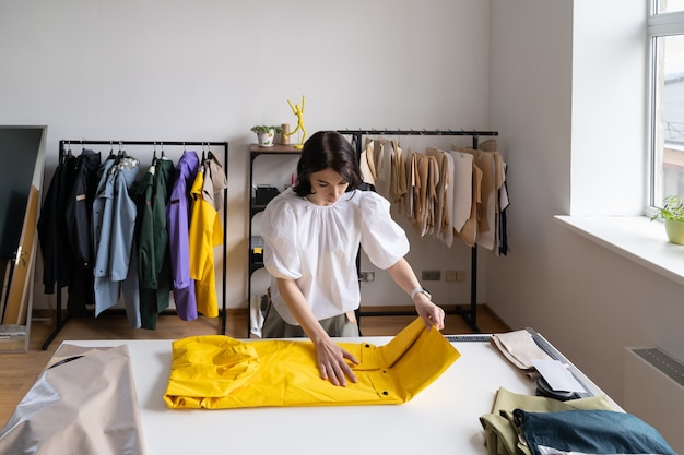 Diseñador de ropa chica abrigo impermeable de nueva colección después de coser en atelier modista en el trabajo