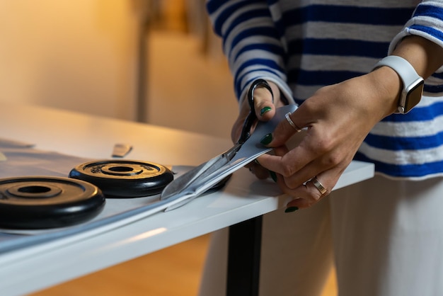 Diseñador de ropa cortó la tela con tijeras y pesas de alcantarillado trabajando en ropa de moda en estudio