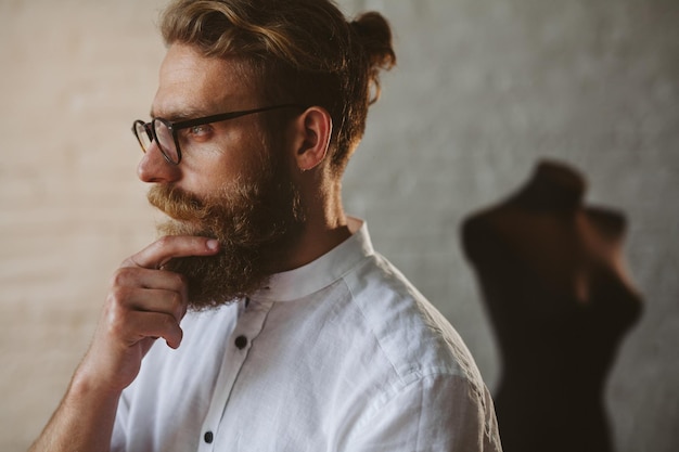 diseñador de ropa joven moderno en el proceso de trabajo, diseñador de ropa con pelo largo y barba