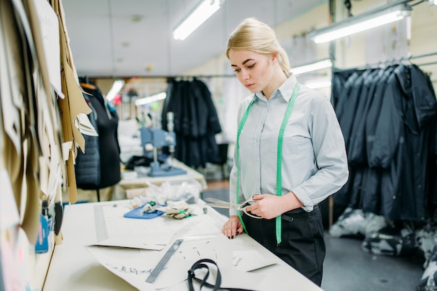 Diseñador de ropa mide un patrón, cosiendo