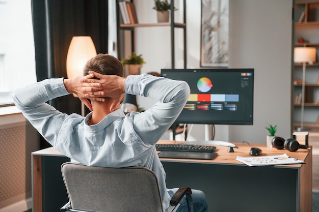 Foto el diseñador está sentado junto a la computadora y usa una tableta gráfica con lápiz