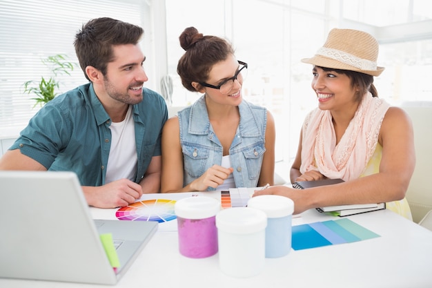 Diseñador sonriente hablando con clientes sobre la carta de colores