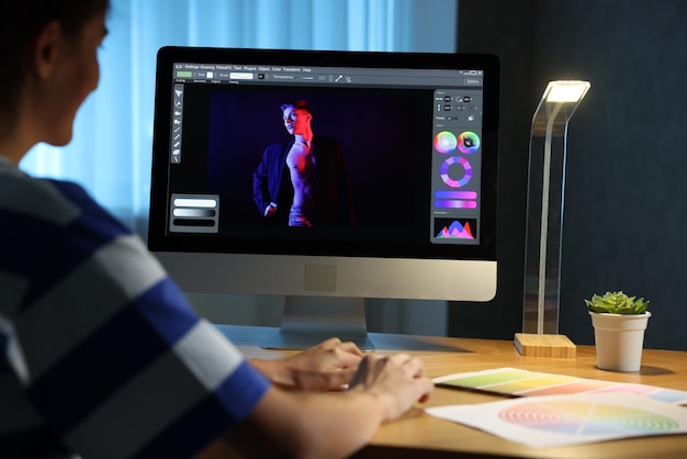 Diseñador trabajando en computadora en interiores de noche en primer plano