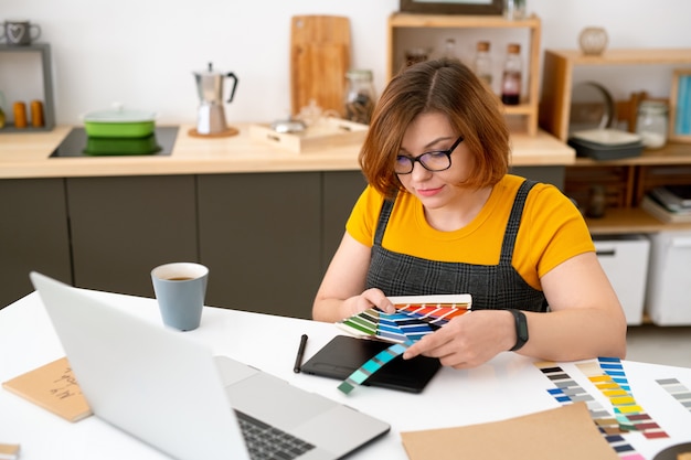 Foto diseñador web joven creativo sentado en el escritorio y mirando la paleta de colores