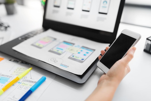 diseñador web con teléfono inteligente y portátil en la oficina
