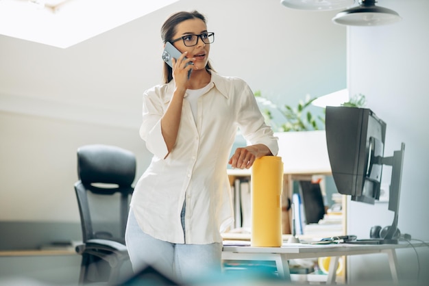 Diseñadora digital femenina hablando por teléfono en una oficina
