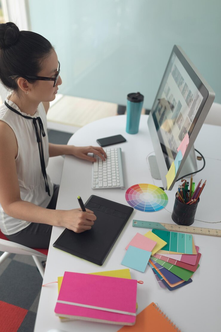 Foto diseñadora gráfica que usa una tableta gráfica en un escritorio en una oficina moderna