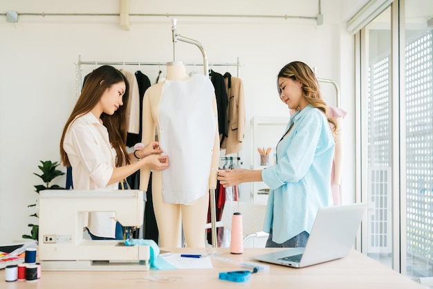 Diseñadora de moda asiática o sastre con asistencia para preparar patrones de tela de papel cortado Modista trabajando y diseñando nuevas colecciones de moda para clientes en el taller de sastrería