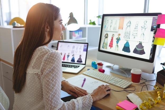 Diseñadora de moda que trabaja en la computadora en el escritorio